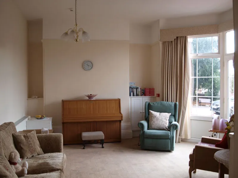 Lounge with armchairs, a piano and a bay window