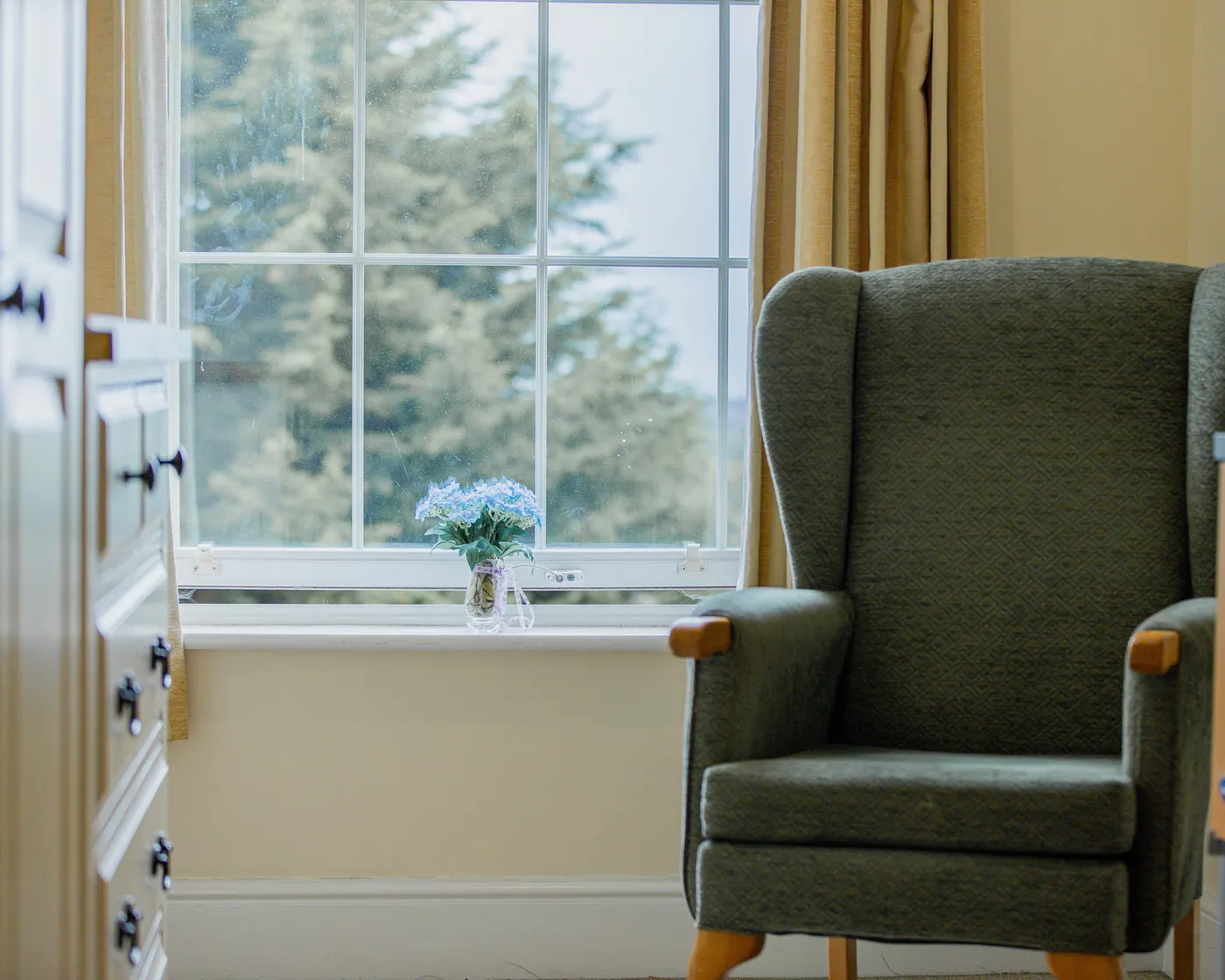 Green armchair by a bedroom window